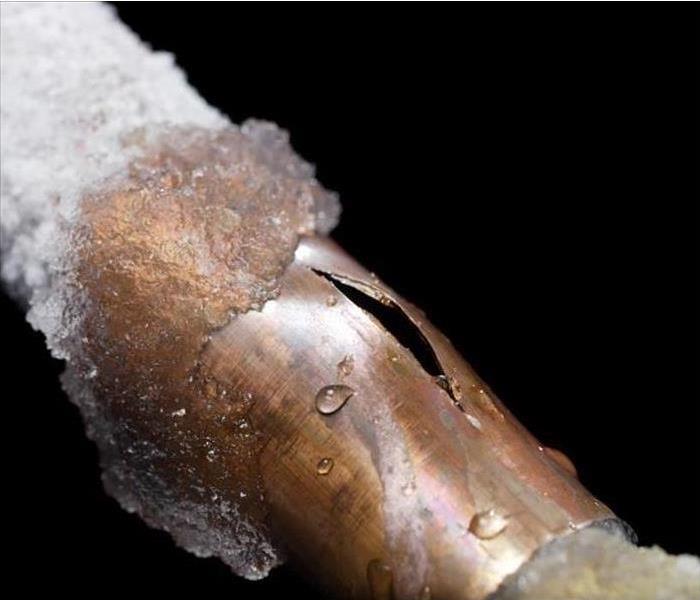 A broken pipe with ice covering it 