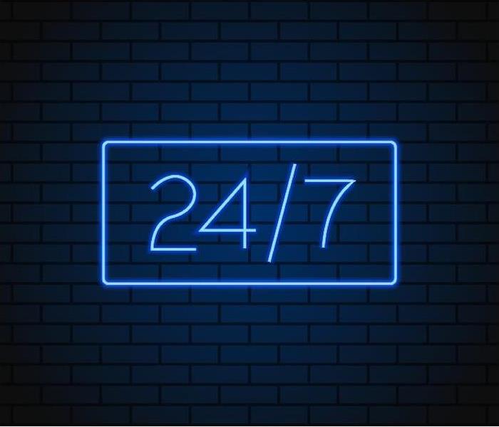 a large 24/7 blue neon sign hanging on brick wall